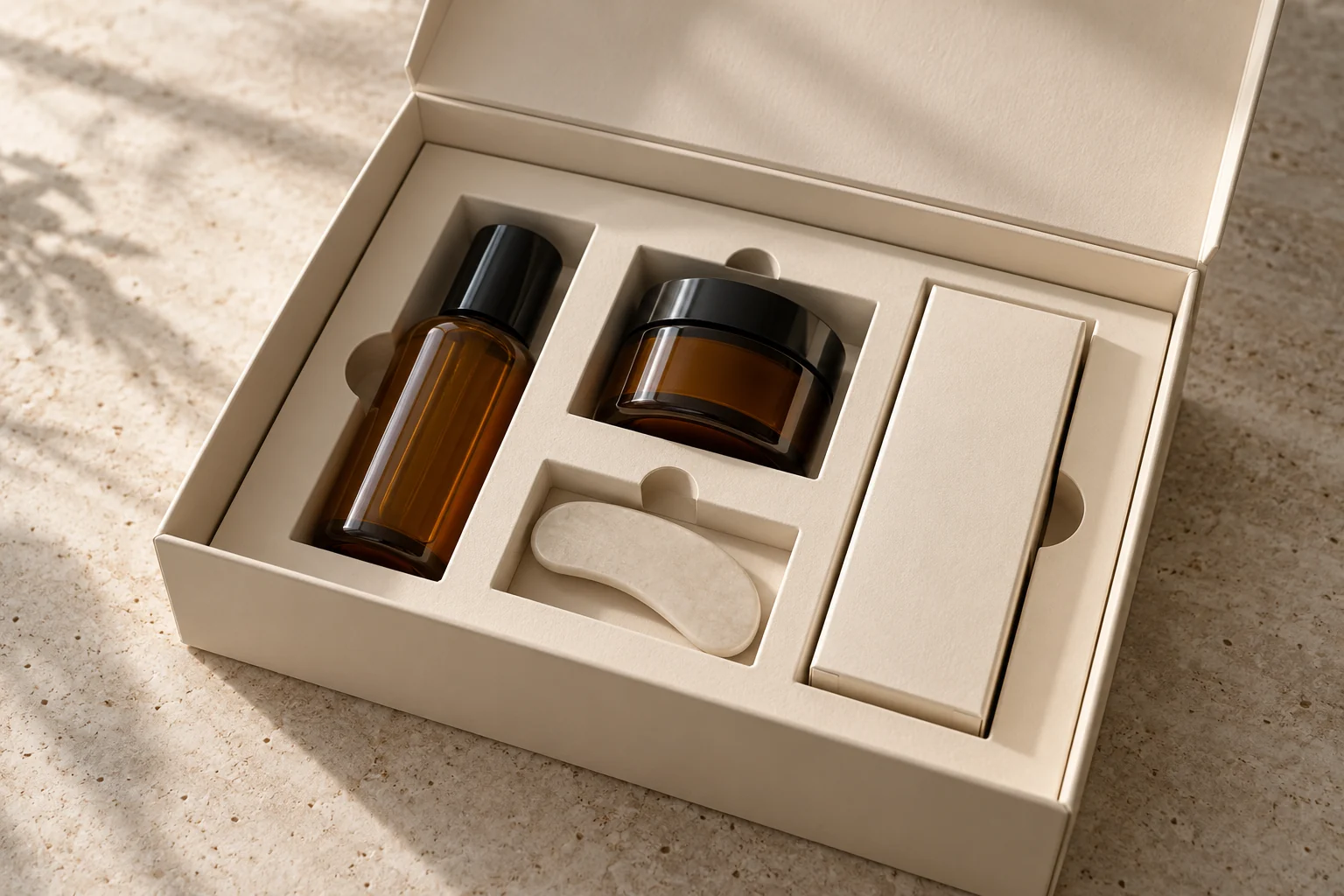 Open rigid gift box with a fitted paperboard insert organizing an amber bottle, jar and accessory